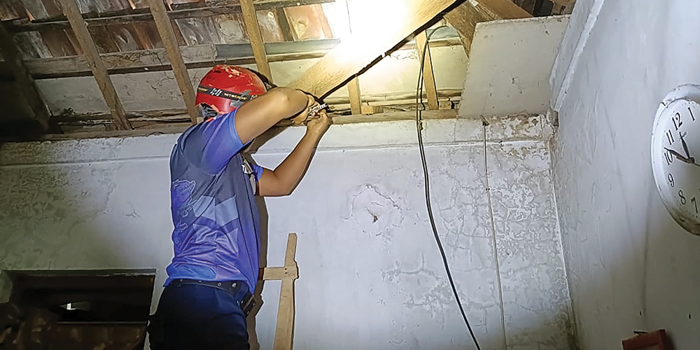 BIKIN GEMPAR: Petugas Damkarmat Nganjuk mengevakuasi ular di atap rumah warga Desa Joho, Pace.