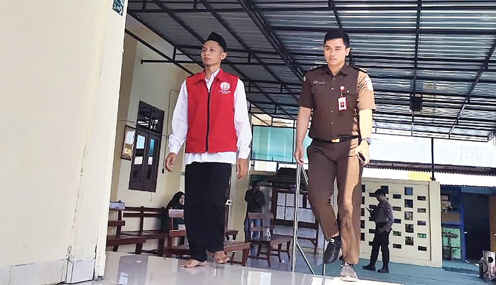 NYEKER: Perampok Alfamart Agil A. Fathoni menuju ruang sidang Pegadilan Negeri Nganjuk kemarin. Agil dituntuu empat tahun penjara karena merampok Alfamart dan Indomart di Nganjuk.