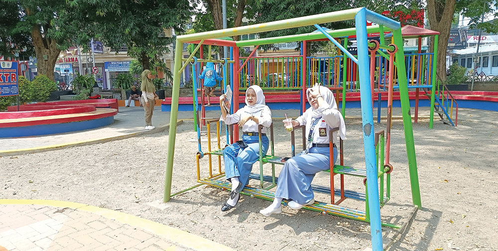 PANAS MENYENGAT: Siswi SMK bermain ayunan di Alun-Alun Nganjuk. Mereka merasa kepanasan karena suhu di Kabupaten Nganjuk rata-rata di atas 34 derajat celcius dalam seminggu terakhir.