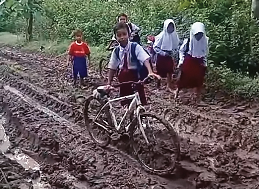 NYEKER: Siswa SDN 3 Perning melewati jalan berlumpur saat pulang sekolah.