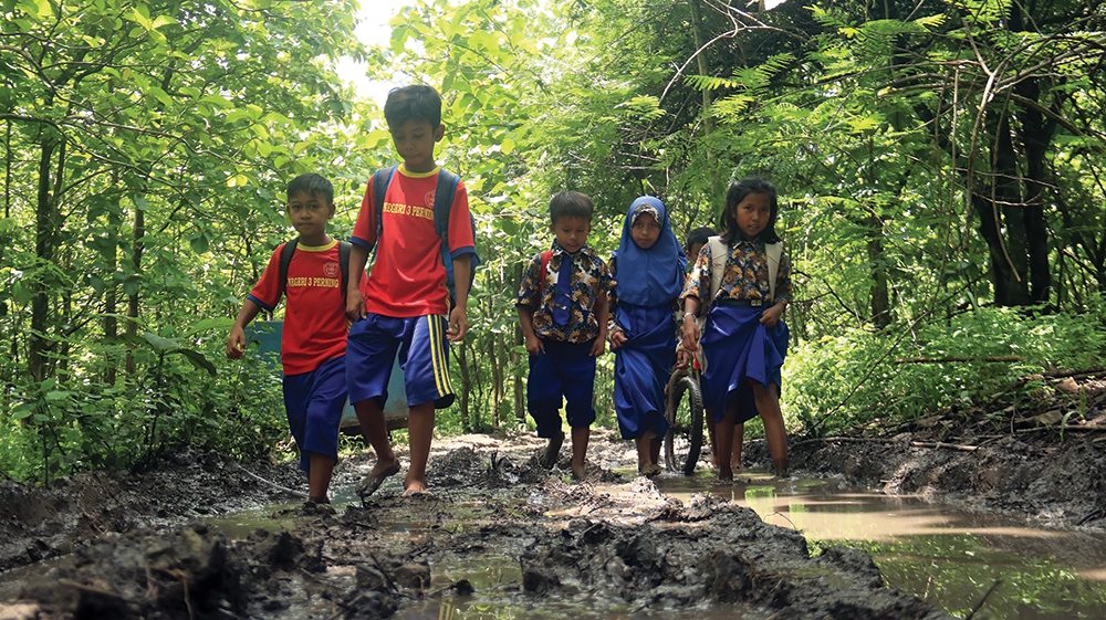 TERJANG HUTAN DAN LUMPUR: Siswa SDN 3 Perning berjalan tanpa alas kaki melewati jalan berlumpur di tengah hutan saat berangkat dan pulang sekolah.