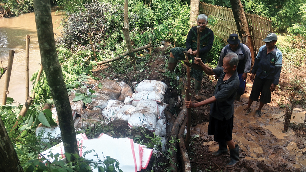 TANGGUL JEBOL: Warga dan perangkat Kelurahan Kapas gotong royong membangun tanggul yang jebol kemarin. Warga minta normalisasi sungai.
