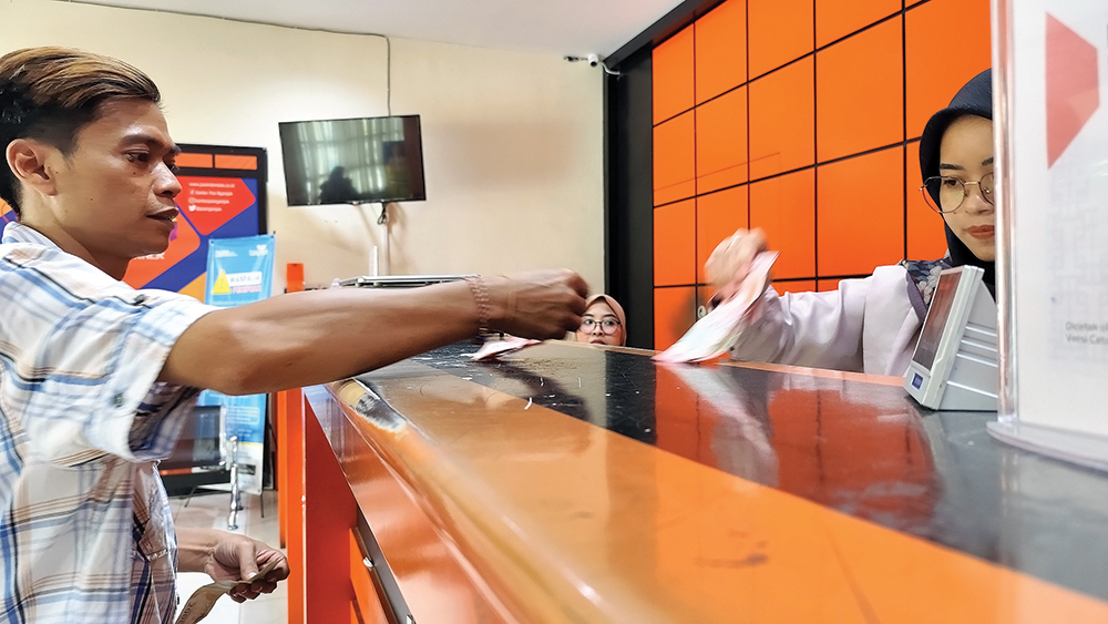 TEMPAT PENCAIRAN: Pegawai Kantor Pos Nganjuk meleyani pelanggan. BLT untuk puluhan ribu KPM cair hari ini.