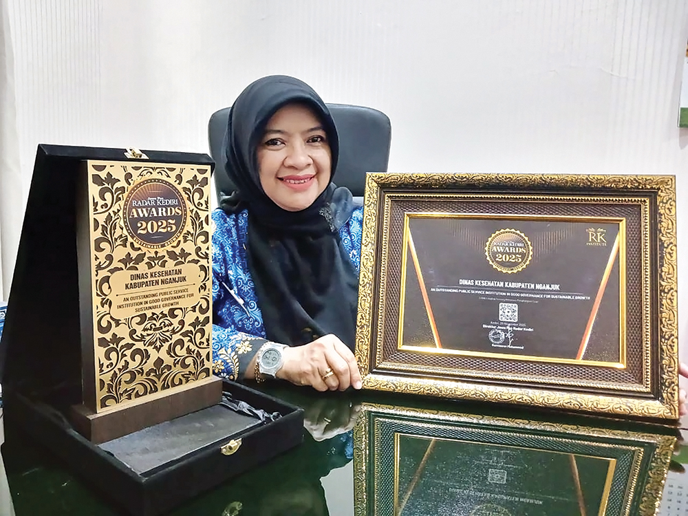 LAMPAUI TARGET: Kepala Dinskes Nganjuk dr Tien Farida Yani menunjukkan piala dan piagam penghargaan Jawa Pos Radar Kediri Awards 2025. Capaian CKG di Nganjuk lampaui target nasional.