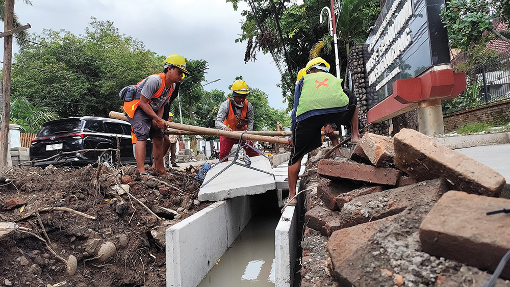 NGEBUT: Pekerja menyelesaikan proyek saluran air di Jalan Merdeka. SPj pencairan molor karena SIPD.