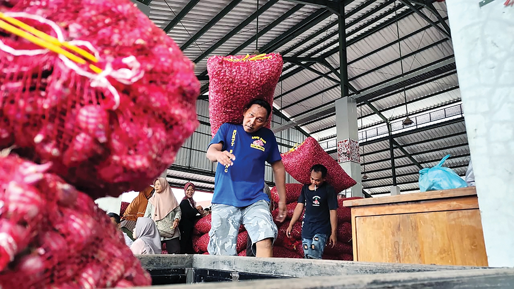 BEBAN BERAT: Pedagang memikul brambang di Pasar Sukomoro kemarin. Harga bawang merah anjlok menjadi Rp 25 ribu per kilogram karena stok melimpah di pasar.