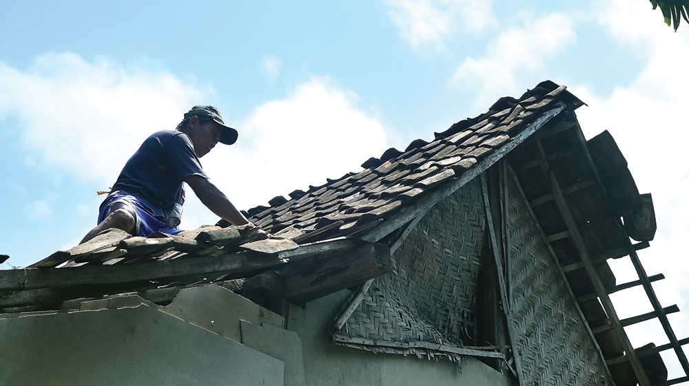 RUSAK BERAT: Warga Dusun Tirip, Desa Sumberurip, Berbek memperbaiki genting yang disapu angin kencang.