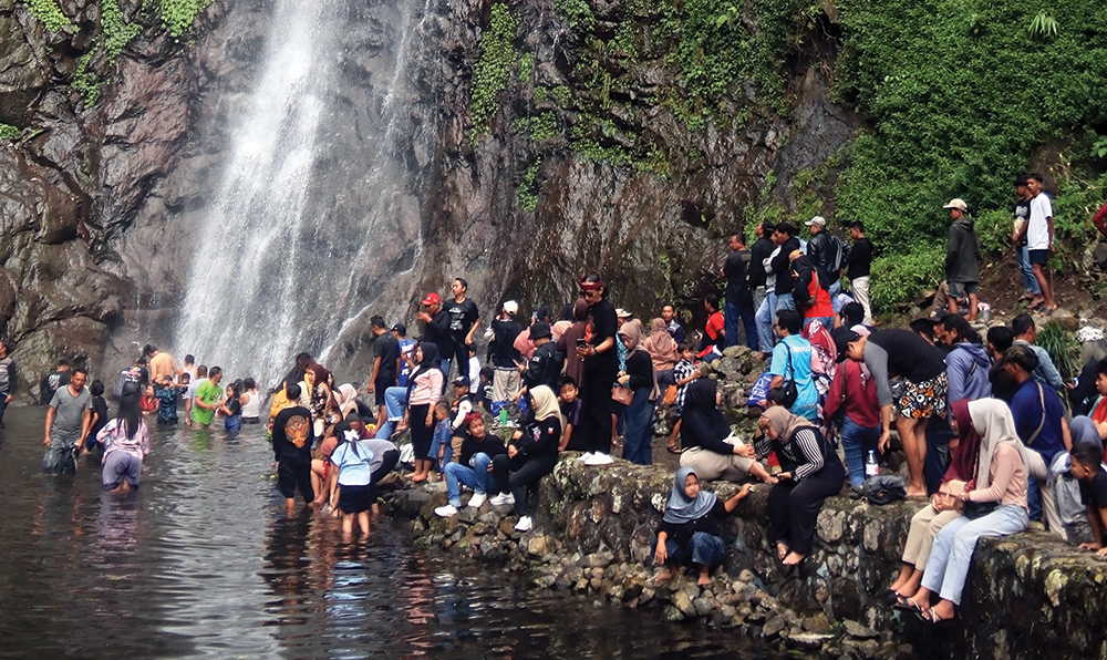 SUMBER PAD: Pengunjung menikmati keindahan Air Terjun Sedudo. PAD Nganjuk tahun 2025 berhasil melampaui target di akhir tahun.