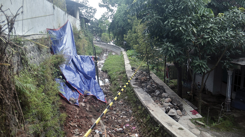 AMBROL: Tanggul Pasar Sawahan dipasang police line dan ditutup terpal karena ambrol kemarin. BPBD dan Disperindag Kabupaten Nganjuk langsung melakukan pengecekan lapangan kemarin.