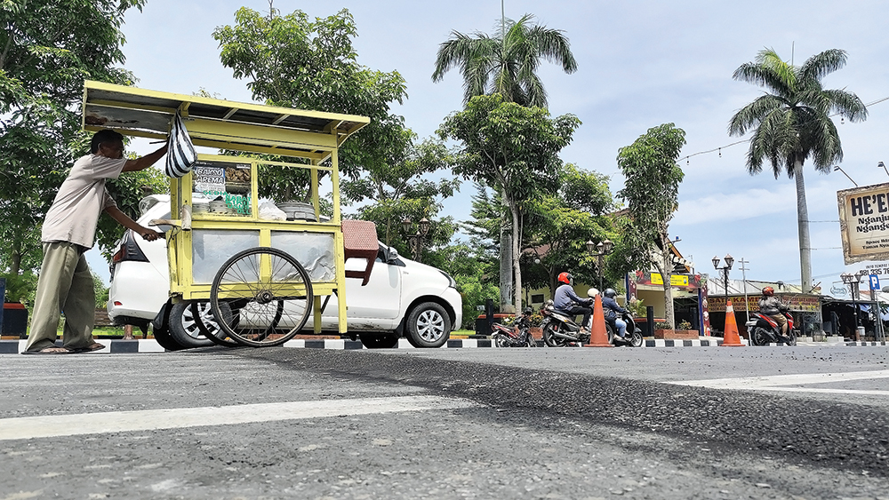 CEGAH LAKA: Tukang bakso melewati speed bump di Jalan A. Yani Nganjuk yang baru dibangun.