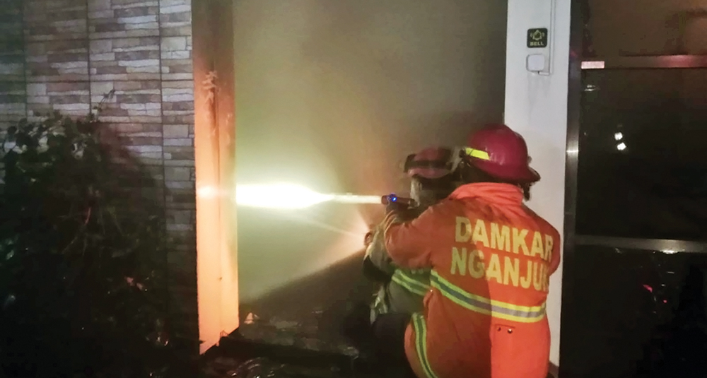JADI ARANG: Petugas Damkarmat Nganjuk memadamkan api yang melalap percetakan Juanda di Jalan Gatot Subroto Nganjuk.