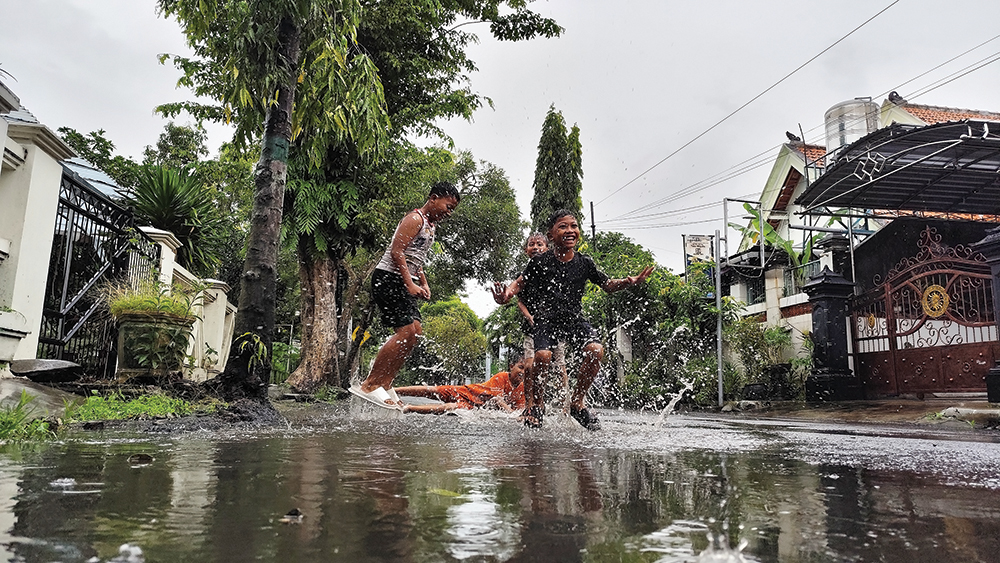 HUJAN SETIAP HARI: Anak-anak bermain air hujan di Jalan Jaksa Agung Suprapto Nganjuk. Cuaca ekstrem ancam Kota Angin pada minggu depan.