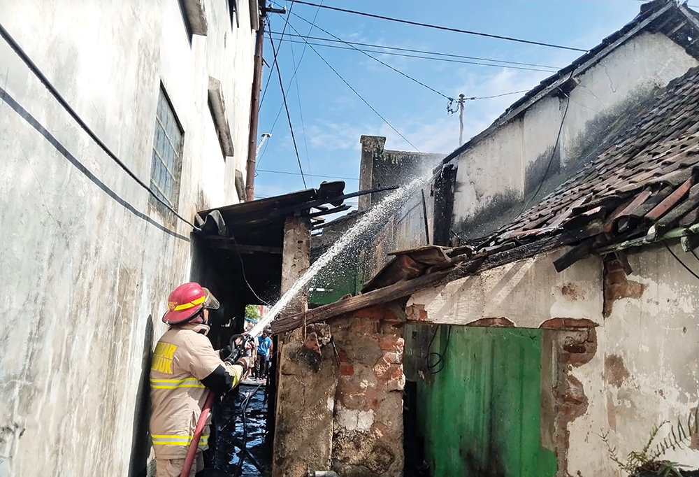 TERBAKAR: Damkarmat memadamkan api yang melalap toko petasan.