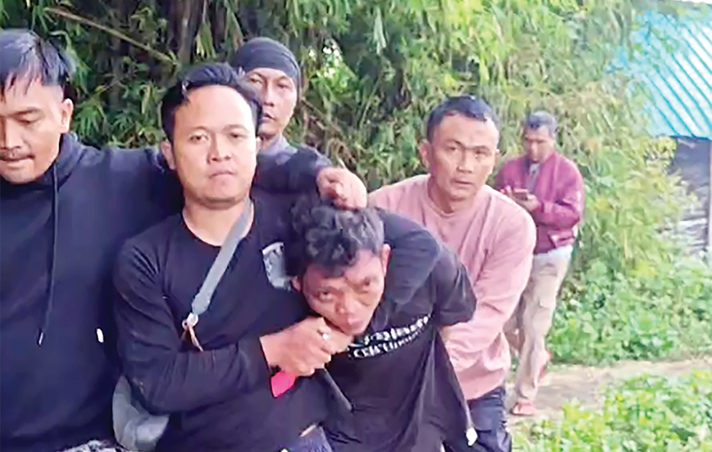 TAK BERKUTIK: Hairul dipiting petugas setelah tertangkap di tumpukan jerami.