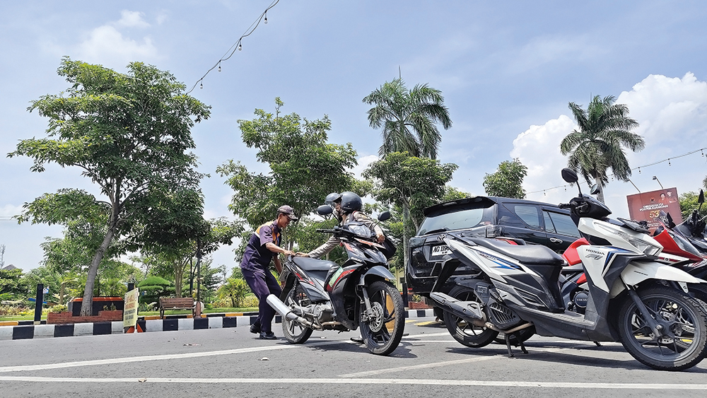 SUMBER PAD: Juru parkir membantu pengendara sepeda motor yang parkir di Jalan Ahmad Yani Nganjuk.