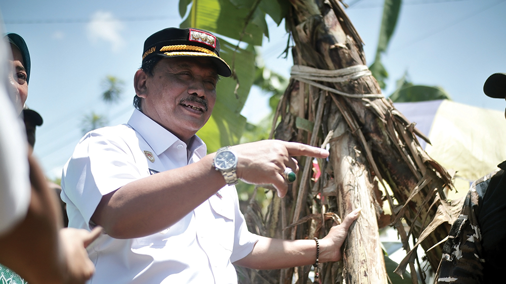 TURUN LANGSUNG: Bupati Marhaen Djumadi memegang pohon pisang yang ditanam warga di jalan berlubang Dusun Miren, Desa Sidoharjo, Kecamatan Tanjunanom kemarin. Kang Marhaen janji segera