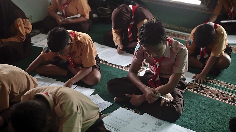 LESEHAN: Siswa kelas VI SDN Balonggebang I di Kecamatan Gondang mengerjakan soal try out Tes Kemampuan Akademik (TKA) di musala karena kelasnya tergenang banjir kemarin.