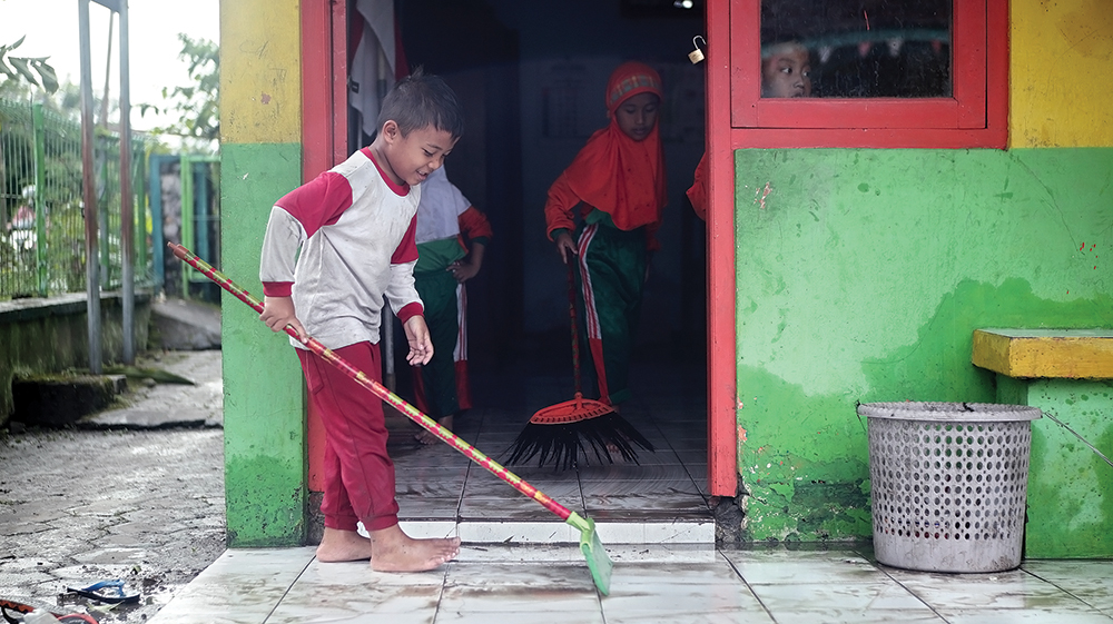 Siswa gotong royong membersihkan lumpur di dalam kelas.