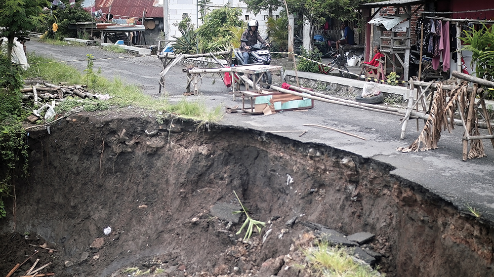 MENGANGA: Aspal di sekitar Jembatan Kedungdowo ambrol kemarin. Pemkab Nganjuk berencana segera memperbaikinya.