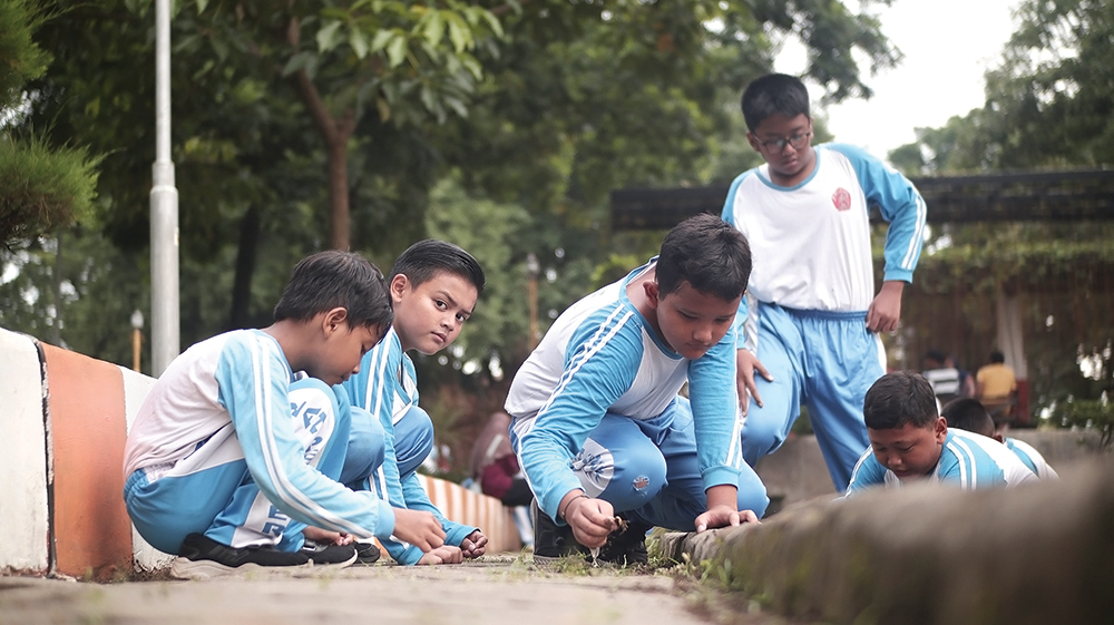 KERJA BAKTI: Siswa SD hingga warga membersihkan rumput di Alun-Alun Nganjuk kemarin.
