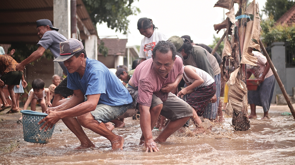 DEMO JALAN RUSAK: Warga Desa Betet, Kecamatan Ngronggot berebut lele yang disebar di jalan rusak kemarin. Warga tanam pohon pisang sebagai bentun protes.