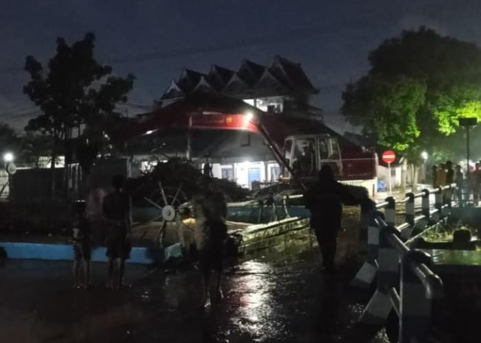 MENCEKAM: Warga menyaksikan luapan air sungai yang mulai masuk ke jalan raya. 