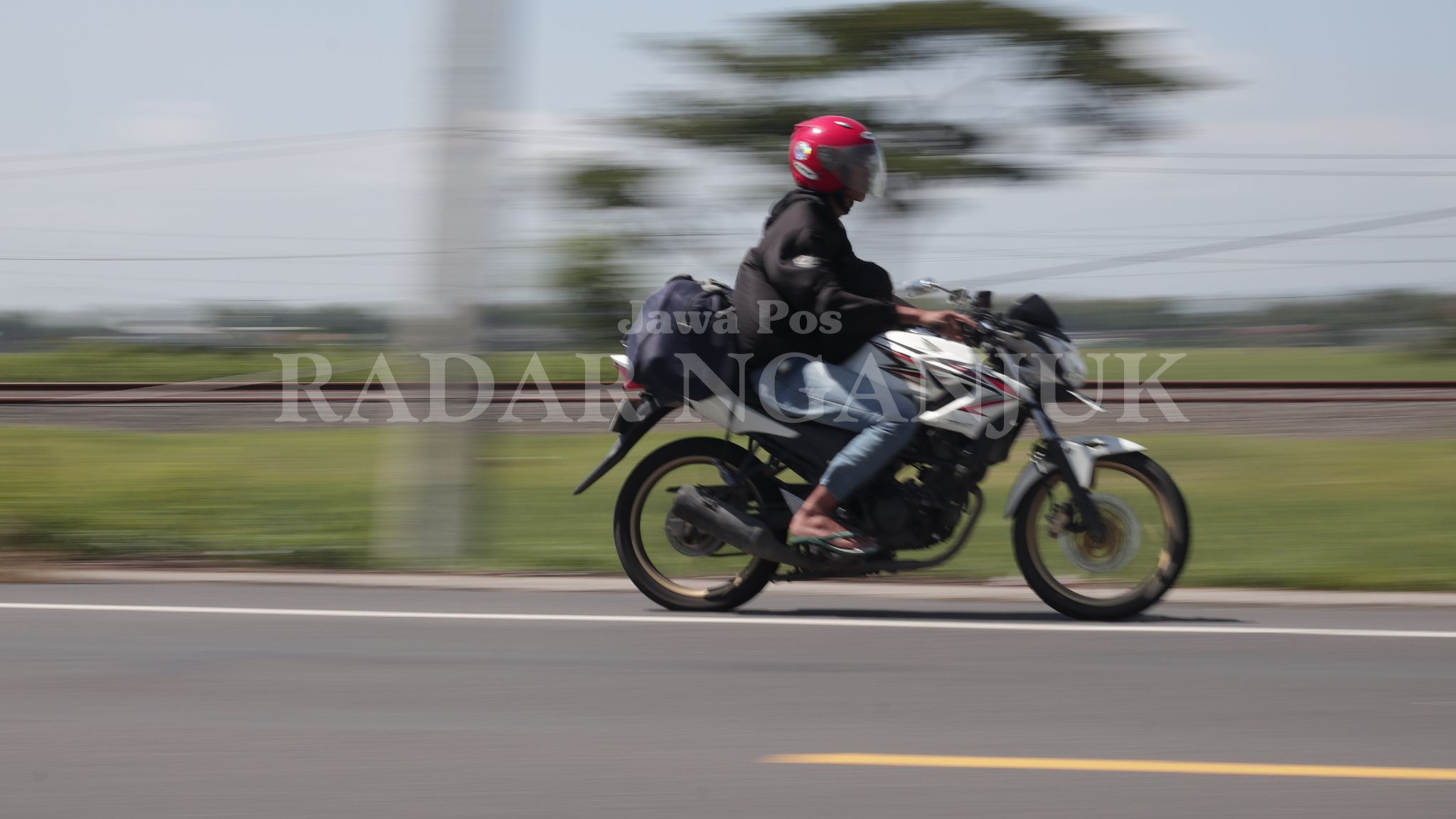 Pengendara sepeda motor membawa barang bawaan