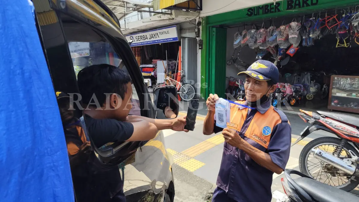 Jukir menunjukkan QRIS untuk pembayaran retribusi parkir luar kota