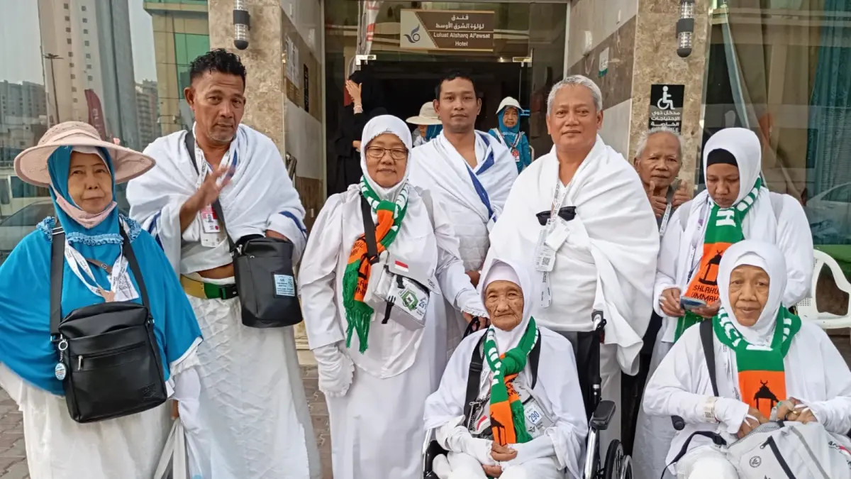 Aris Nasution, Kepala MTs Aisiyah Nganjuk mendorong Mbah Marsyiah yang duduk di kursi roda (tengah) saat menunaikan Ibadah Haji 2026. 