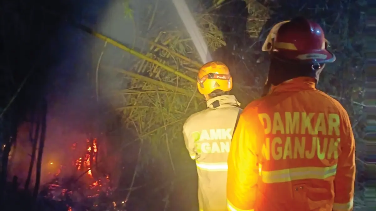 MEMBARA: Petugas Damkarmat Nganjuk memadamkan api yang melalap rumpun bambu karena puntung rokok. (novanda nirwana/jprk)
