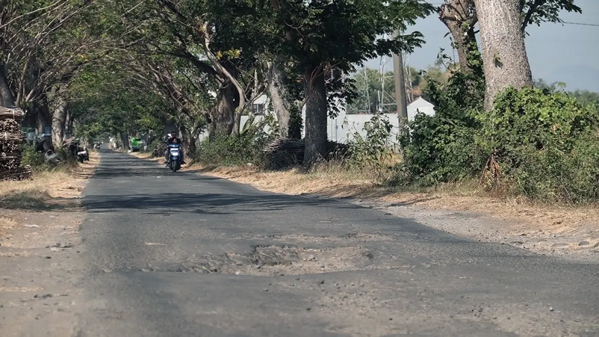 TERKENDALA EFISIENSI: Pengendara sepeda motor melintas di Jalan Kelurahan Kapas, Sukomoro yang rusak. (karen wibi/jprk)