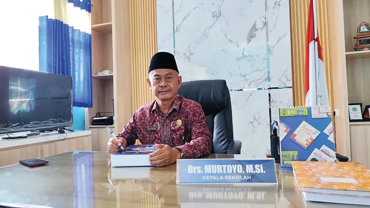 Dekat Dengan Siswa: Kepala SMAN 2 Nganjuk Murtoyo membaca buku di ruang kerjanya. (rekian/jprk)