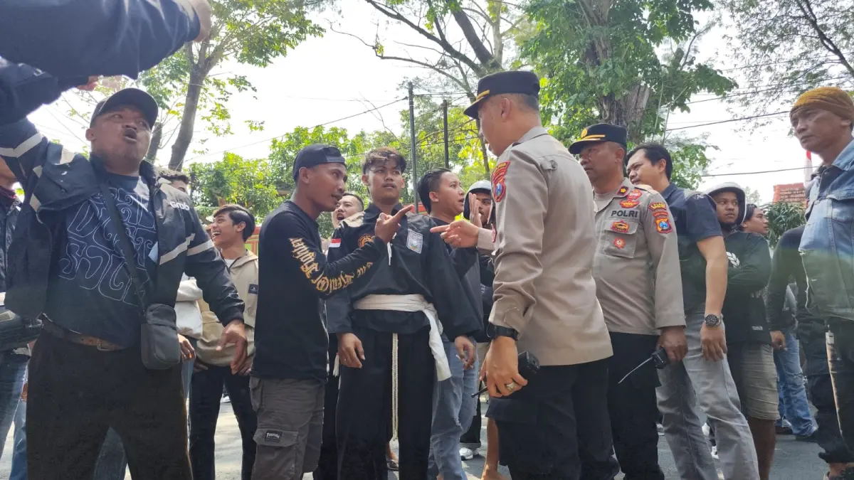 MEMANAS: Ratusan warga PSHT bersitegang dengan polisi di halaman Pengadilan Negeri (PN) Nganjuk kemarin. Mereka mengawal sidang tuntutan pengeroyokan Minal Kosirin hingga tewas yang dilaksanakan tertutup. (novanda nirwana/jprk)
