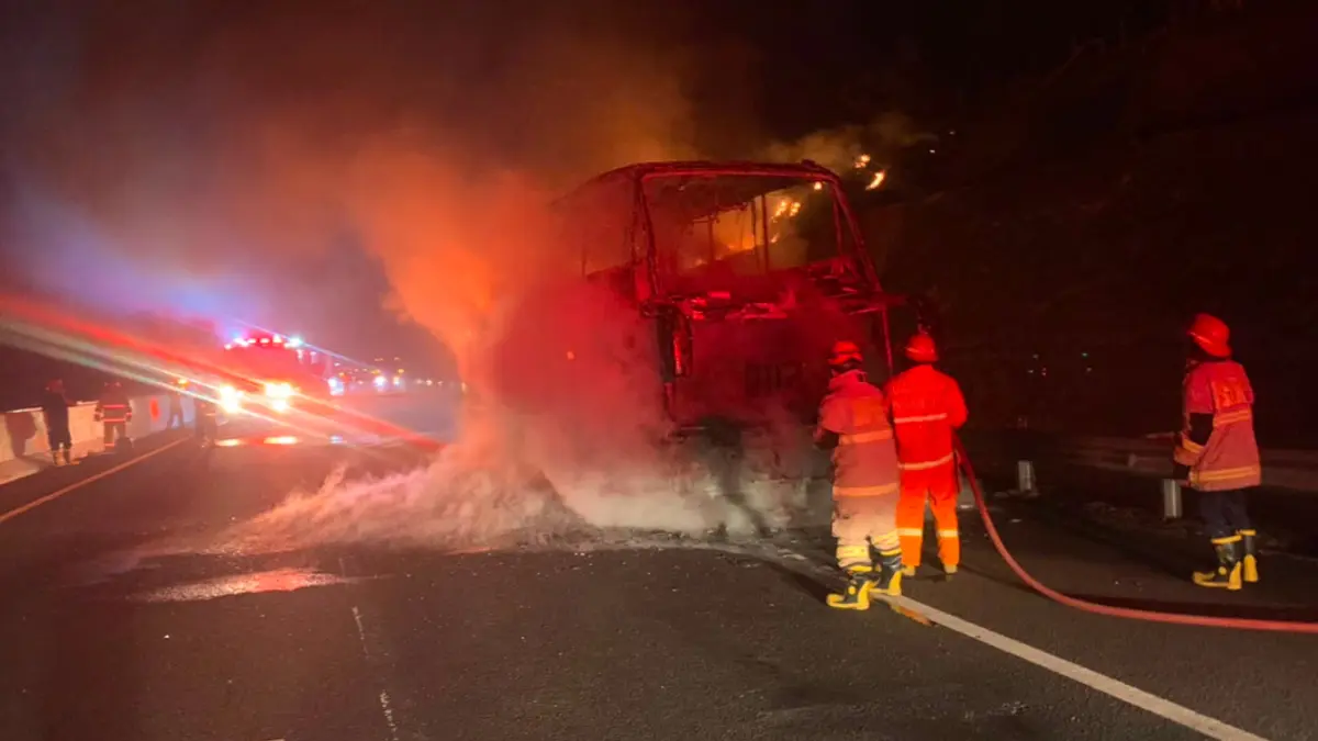 Petugas Pemadam Kebakaran Dan Penyelamatan (Damkarmat) Nganjuk memadamkan api yang mengamuk di Bus PO Gunung Harta saat berapa di Jalan Tol Nganjuk.  