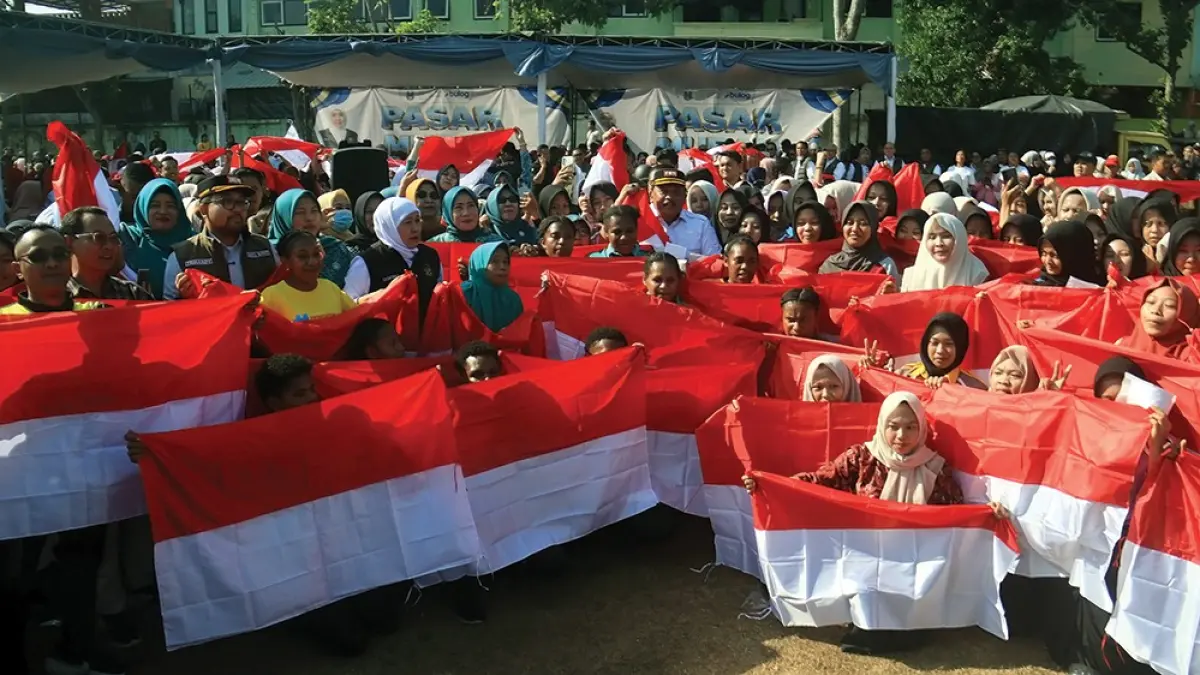 SEMANGAT: Bupati Marhaen bersama warga membentangkan Bendera Merah Putih saat Pasar Murah bersama Pemprov Jawa Timur (Jatim). (karen wibi/jprk)