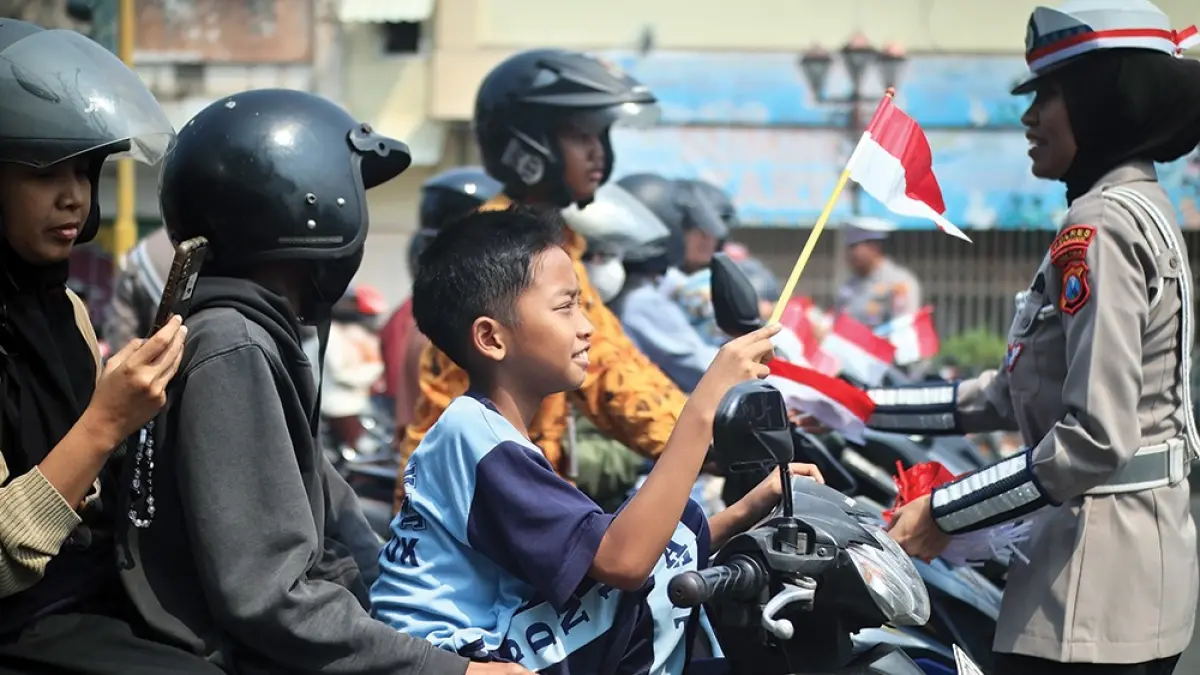 MOMEN KEMERDEKAAN: Polwan membagikan bendera Merah Putih pada pengguna jalan setelah detik-detik proklamasi di Jalan Ahmad Yani Nganjuk kemarin. (karen wibi/jprk)