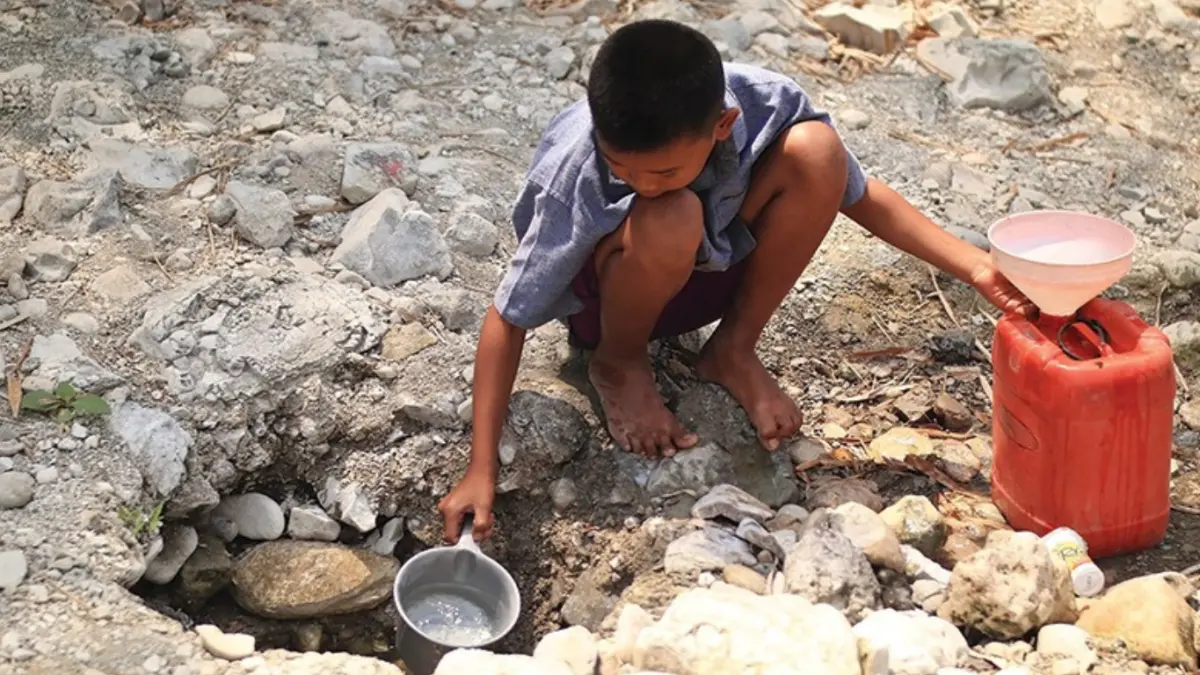 Bocah asal Desa Ngepung, Kecamatan Lengkong, Nganjuk mengambil air bersih yang tergenang di tengah sungai yang mengering. 