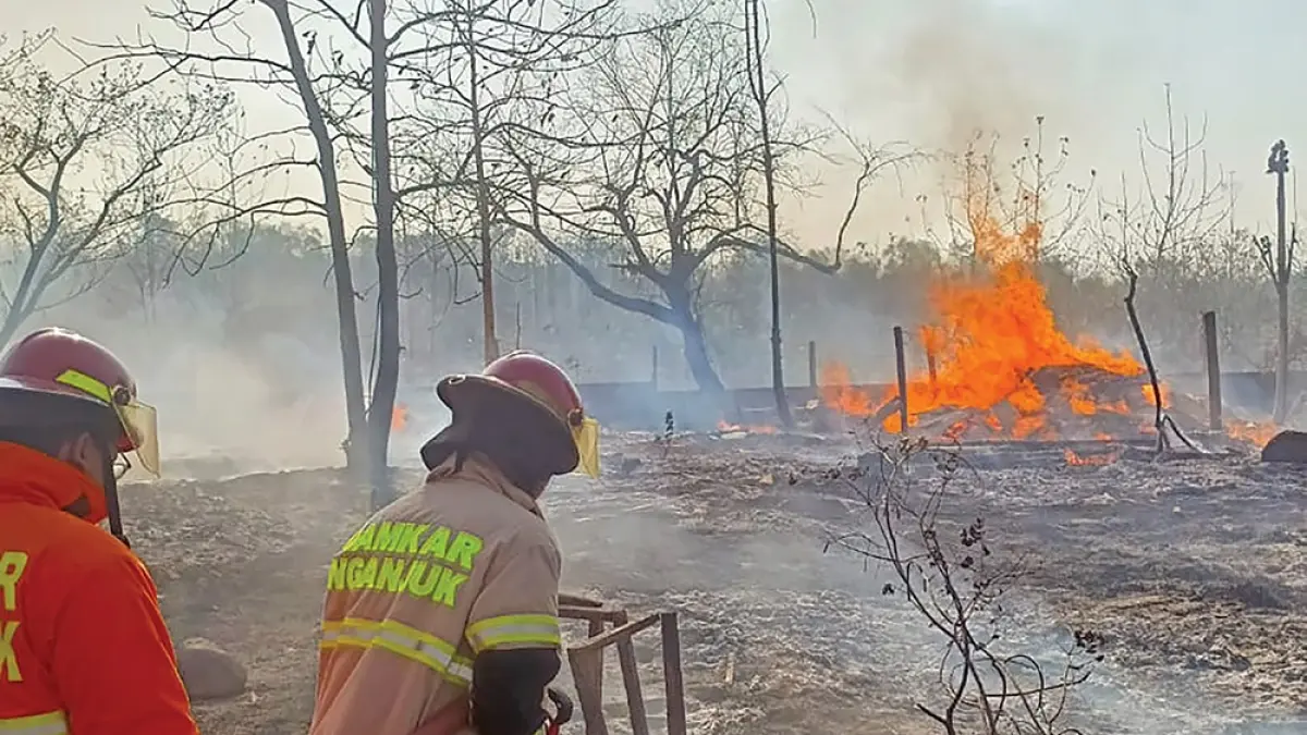 JADI ARANG: Petugas Damkarmat Nganjuk memadamkan si jago merah yang melalap gudang kayu di Desa Ngepeh, Loceret. (novanda nirwana/jprk).