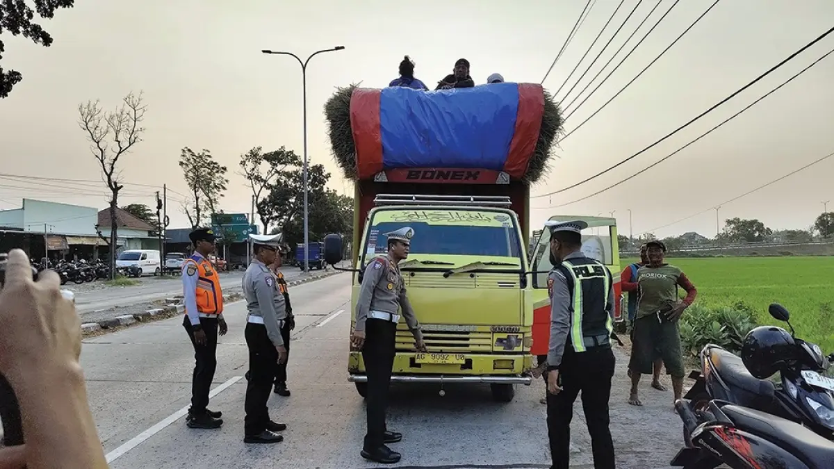 BERBAHAYA: Petugas Satlantas Polres Nganjuk menilang sopir truk yang mengangkut 12 orang di bak truk. (novanda nirwana/jprk)