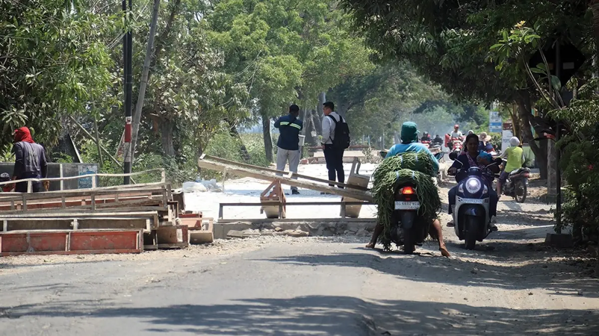 BERBAHAYA: Pengendara sepeda motor melintas di Jalan Raya Kecubung-Sukomoro kemarin. Tinggi jalan baru dengan yang lama lebih dari 20 cm membuat rawan terjadi kecelakaan atau terjatuh. (karen wibi/jprk)