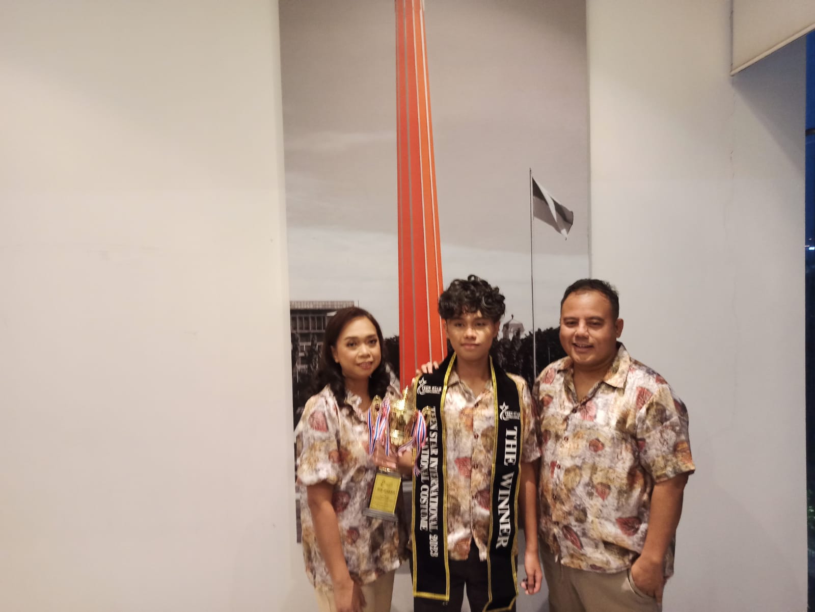 Azriel Emeraldo Mukti Andima bersama kedua orang tuanya menunjukan piala juara dalam ajang Teen Star International di Thailand.