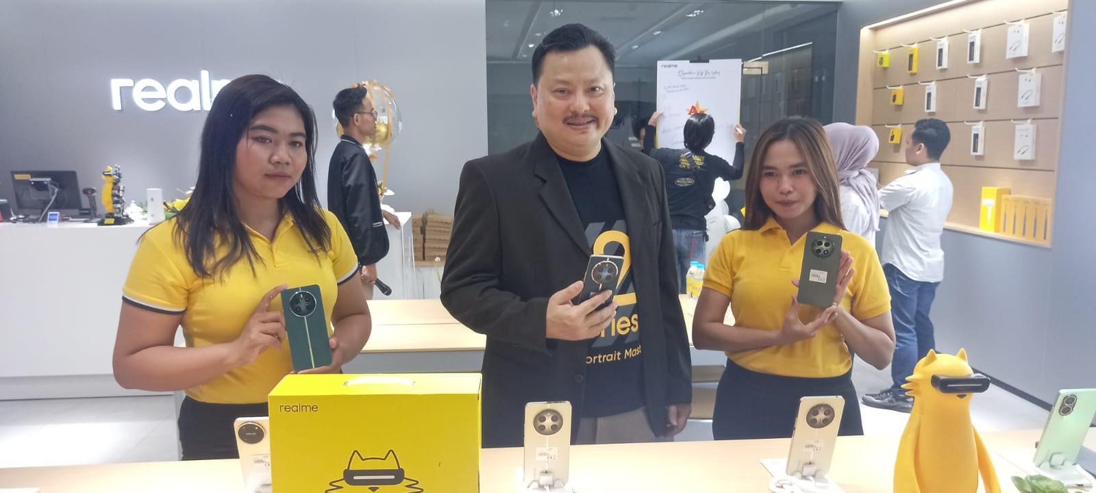 Rony Candra, Owner Asia Jaya bersama tim sales menunjukkan smartphone realme 12 series.