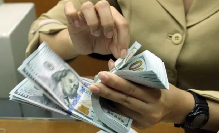 TUKAR: Pegawai money changer menghitung uang dolar Amerika Serikat yang akan ditukar dengan mata uang rupiah. (JAWA POS)
