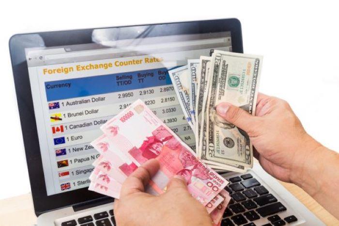 BERHITUNG: Seorang karyawan di bisnis penukaran asing sedang menghitung rupiah yang akan dibelikan dollar Amerika Serikat. (UMA.AC.ID)