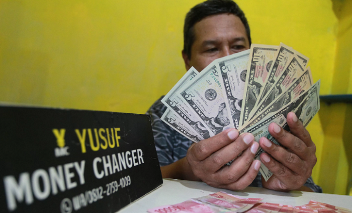 ILUSTRASI: Petugas menghitung mata uang rupiah dan dolar AS di sebuah money changer. (RADAR JOGJA)