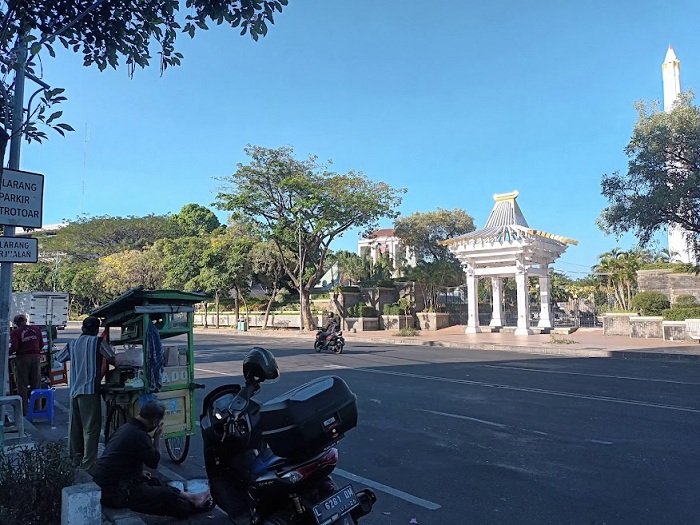 MELIPIR: Seorang pengendara motor berteduh di bawang pohon karena tak tahan dengan cuaca Kota Surabaya yang panas.