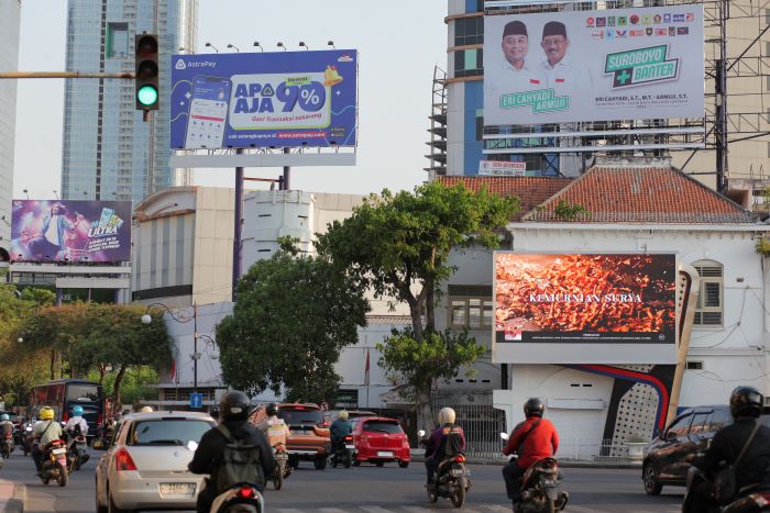 BANYAK REKLAME: Pengendara kendaraan melintas tak jauh dari papan reklame di kawasan Jalan Tunjungan, Surabaya.