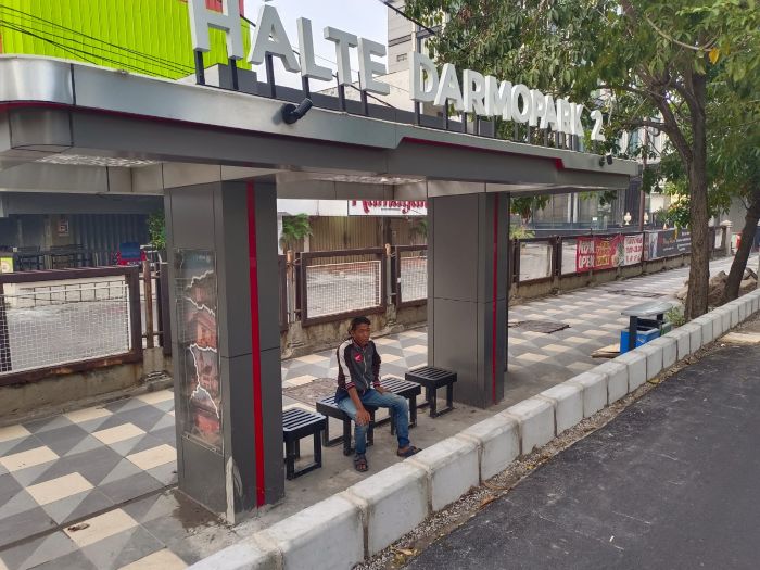 SANTAI: Seorang warga menunggu angkutan umum di Halte Darmo Park 2, Jalan Mayjend Sungkono, Surabaya.
