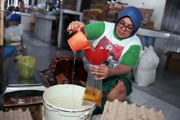 HARGA NAIK: Seorang pekerja menakar minyak goreng curah untuk selanjutnya dikemas dengan ukuran per kilogram.