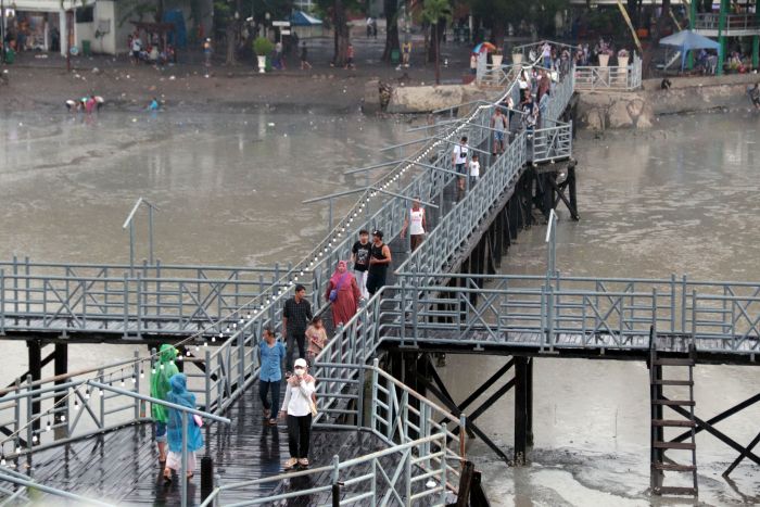 RAMAI: Tempat Hiburan Pantai (THP) Kenjeran, Surabaya, tetap diserbu warga untuk mengisi libur Tahun Baru 2025 meskipun hujan deras mengguyur wilayah tersebut, Rabu (1/1/2025).